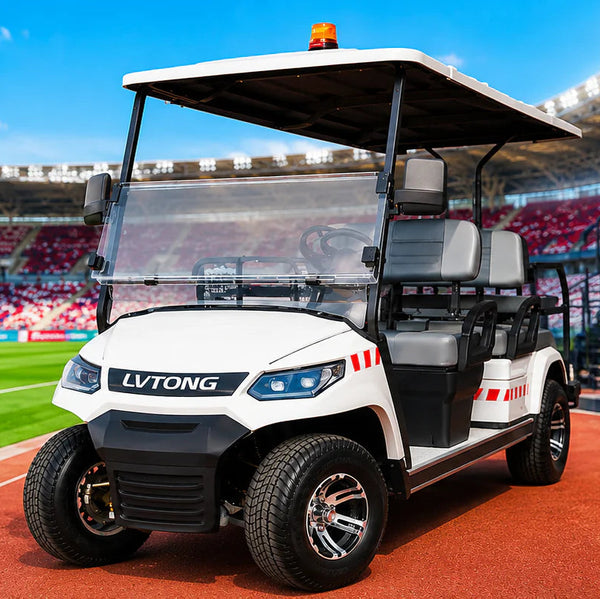 A white and black LV TONG electric golf cart with an orange beacon light is parked on a red track next to a stadium building with a medical room sign. In the background, a soccer stadium with red seats and a stretcher with medical supplies is visible under a blue sky.